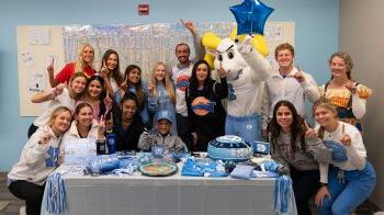 Craniofacial team poses at table with birthday cake